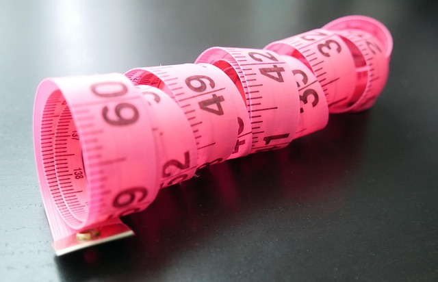 A pink coiled measuring tape on a dark surface