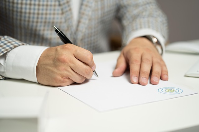 A person in a suit signing a document with a pen