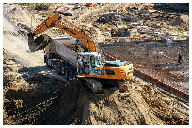 An excavator loading dirt into a dump truck at a construction site