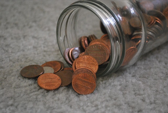 Glass jar tipped over with pennies spilling out onto carpet