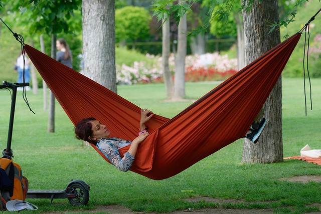 A woman relaxing in an orange hammock in a park