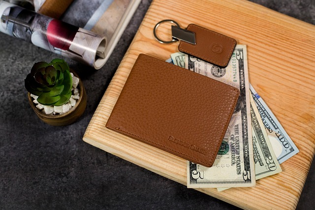 A brown leather wallet with US dollars on a wooden board