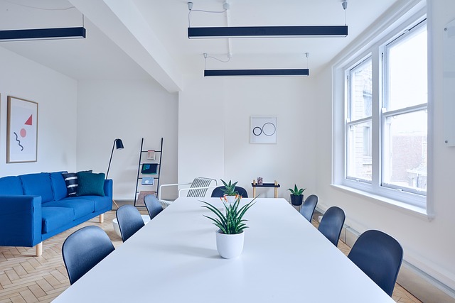 A modern minimalist room with a long white table and blue sofa