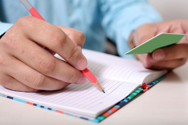 A person writing in a notebook with a pencil