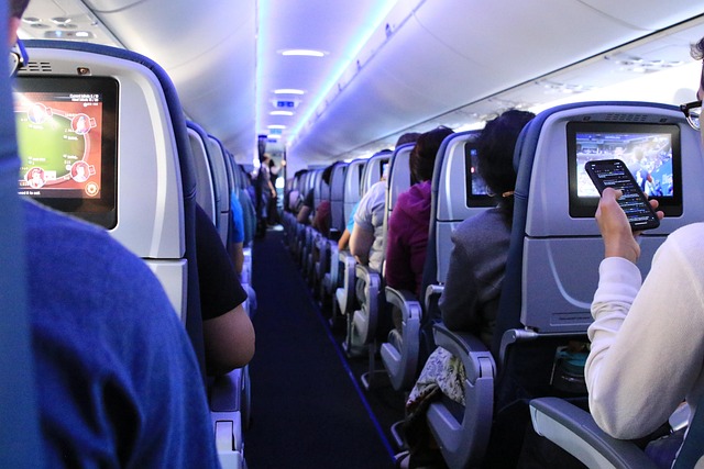 Airplane cabin with a passenger using a smartphone in their seat