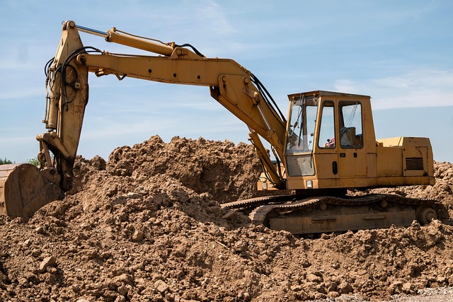 A yellow excavator working on a mound of dirt