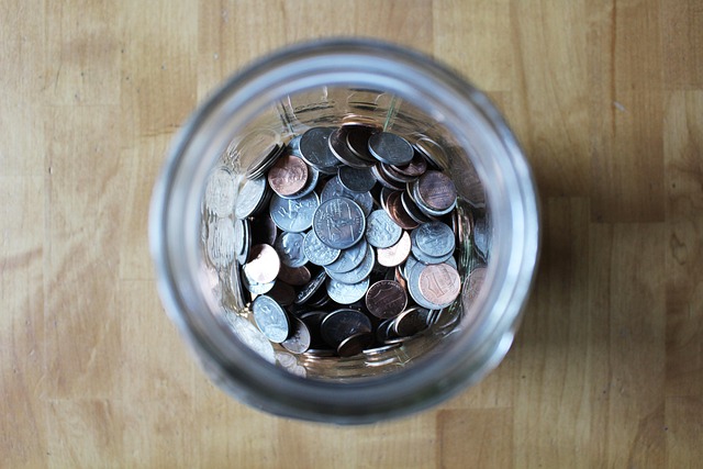 Top view of US coins inside a glass jar on wood