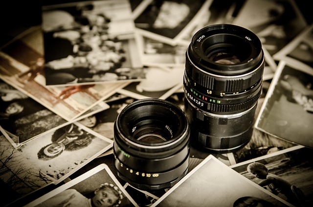 Camera lenses sitting on a pile of old printed photographs