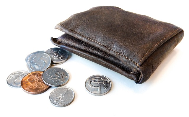 A brown leather wallet next to several coins