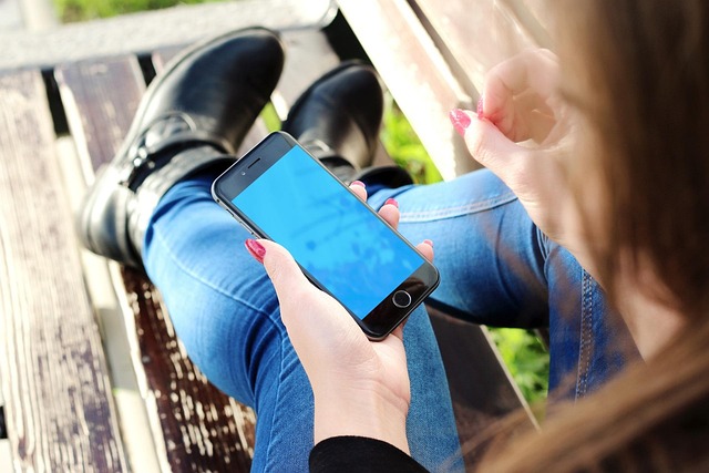 A person holding a smartphone while sitting on a bench
