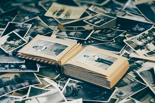 An open photo album surrounded by scattered vintage black and white photographs