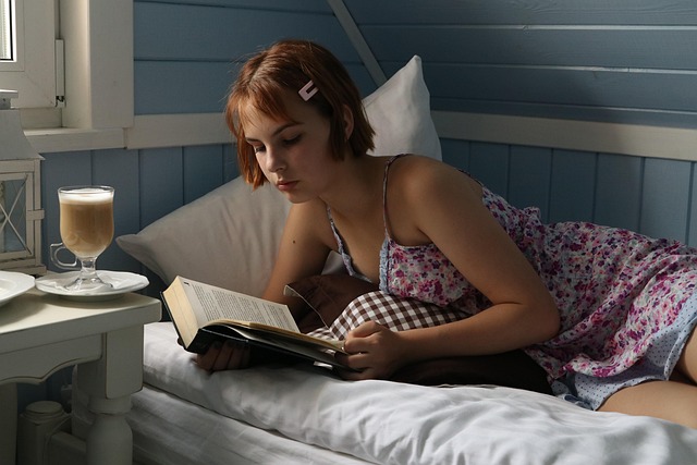A young woman lying in bed reading a book
