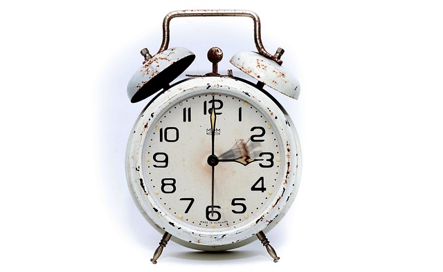 A vintage white alarm clock on a plain background