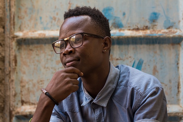 A man wearing glasses resting his chin on his hand thoughtfully