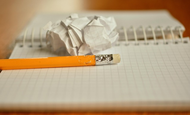 A pencil and a crumpled piece of paper on a notebook
